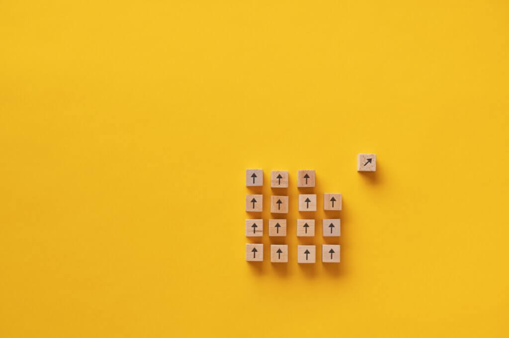 Capa do artigo Transição de carreira para tecnologia em que quadrados de madeira aparecem em um fundo amarelo enquanto um desses quadrados está mudando de rota.