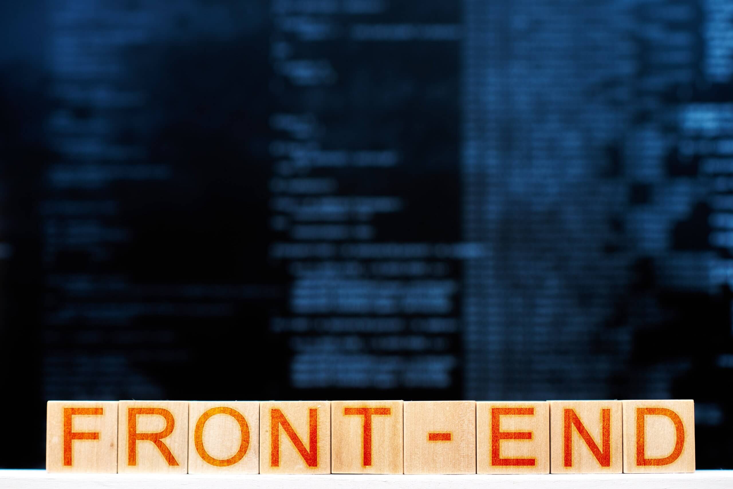 Capa do Artigo desenvolvimento front-end onde se lê a palavra "front-end" escrita em um quadrado de madeira e letras vermelhas, atrás há códigos de programação embaçados.