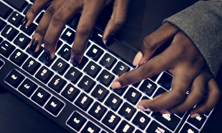 Capa do artigo sobre Kubernetes em que vemos um closeup em mãos negras com as unhas pintadas trabalhando no teclado do computador.