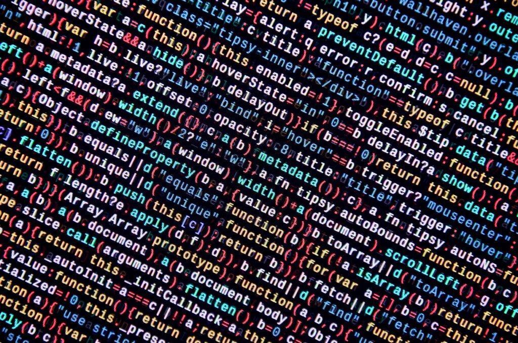 Capa do artigo sobre processos de Code Review com Inteligência Artificial em que vemos códigos de programação com letras, símbolos e números coloridos em um fundo escuro.