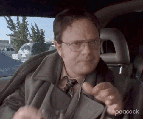 Gif do personagem da série The Office Dwight pegando um binóculo e colocando no rosto para observar melhor algo