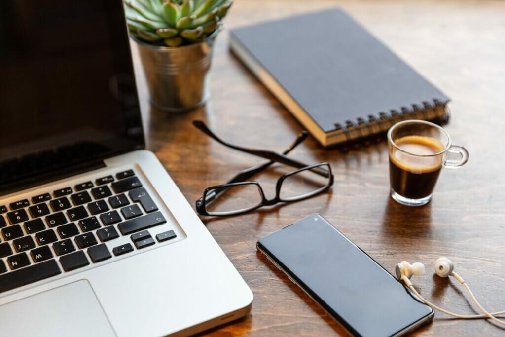 Capa do artigo sobre bibliotecas Android. Na foto, aparece um celular, um notebook, um óculos, um caderno de anotações, um café e fones de ouvido em cima de uma mesa.