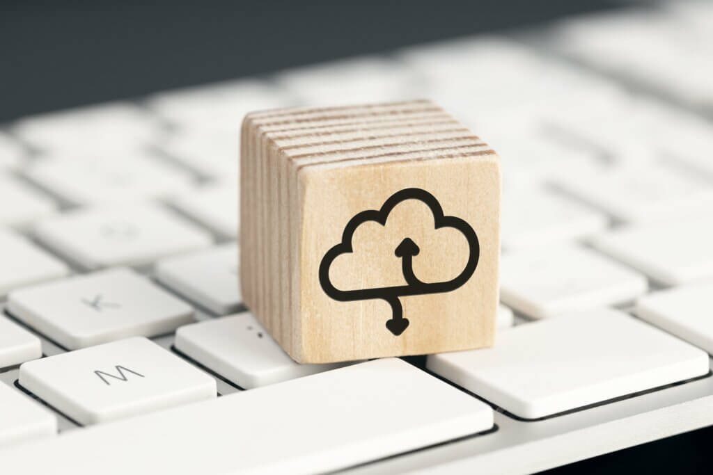 Capa do artigo sobre computação em nuvem. Na imagem, vemos o símbolo de computação em nuvem em um bloco de madeira, que está apoiado em um teclado branco.