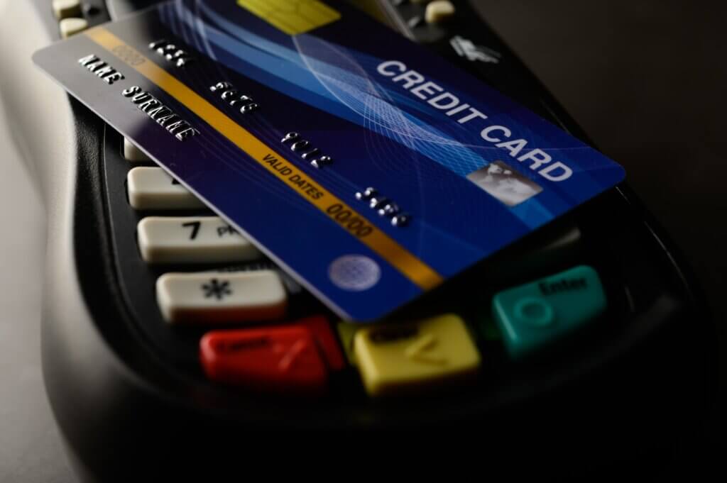 Capa do artigo sobre PCI-DSS. Na imagem, um cartão de crédito azul está em cima de uma maquininha de cartão.