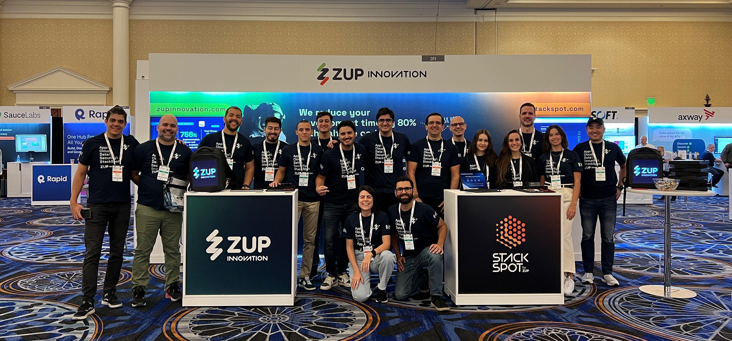 Foto de capa do conteúdo "Gartner Application Innovation 2023" com 17 pessoas de camiseta azul escura representando a Zup Innovation e StackSpot. Atrás está o estande da empresa com um painel e a frente dois tótens.
