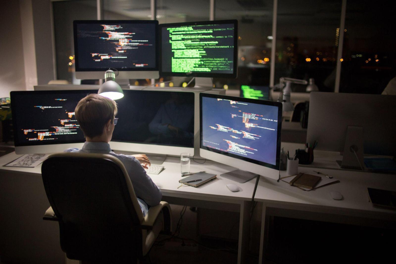 Imagem capa do conteúdo sobre "Jupyter notebook", onde exibe uma vista traseira do codificador altamente profissional olhando para relógio de pulso enquanto está sentado na frente do computador e trabalhando no interior do escritório.